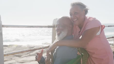 Happy-senior-african-american-couple-embracing-on-promenade-by-the-sea,-slow-motion