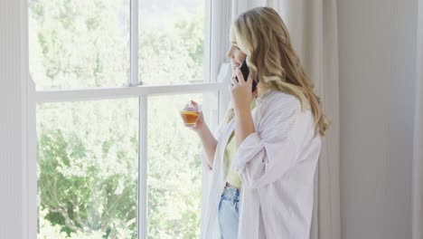 Happy-caucasian-plus-size-woman-talking-on-smartphone-and-drinking-tea-in-slow-motion