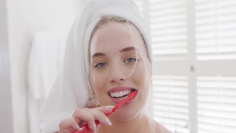 Portrait-of-happy-caucasian-plus-size-woman-with-towel-on-head-brushing-teeth-in-slow-motion