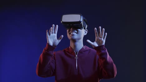 Asian-man-using-vr-headset,-touching-virtual-screen-on-blue-background,-slow-motion