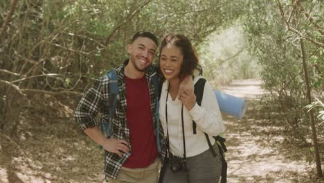 Portarit-of-happy-african-american-couple-wearing-backpack,-embracing-in-forest,-slow-motion