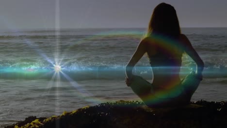 Animation-Von-Lichtflecken-über-Einer-Kaukasischen-Frau,-Die-Am-Strand-Yoga-Praktiziert-Und-Meditiert