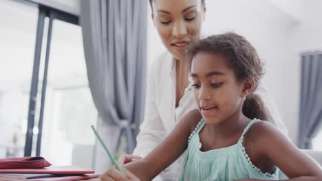 African-american-mother-and-daughter-sitting-and-table-and-doing-homework-together,-slow-motion