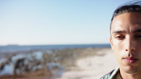 Portrait-of-biracial-man-looking-at-camera-at-promenade-by-the-sea-with-copy-space,-slow-motion