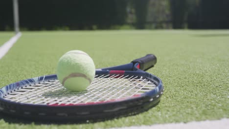 Close-up-of-tennis-racket-and-ball-on-tennis-court-on-sunny-day
