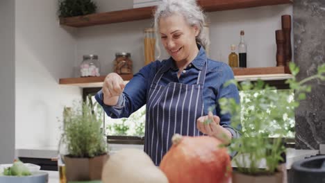Smiling-senior-caucasian-woman-seasoning-vegetables-in-kitchen,-slow-motion