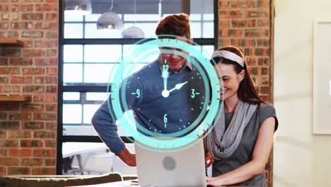 Animation-of-clock-ticking-over-diverse-business-people-using-laptop
