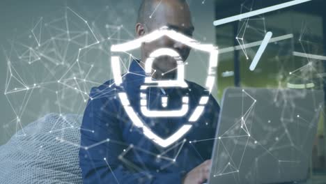 Animation-of-padlock-in-shield,-connected-dots-over-african-american-businessman-working-on-laptop