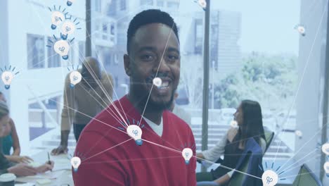 Animation-of-network-of-bulb-icon-against-african-american-man-smiling-at-office