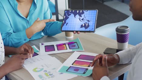Biracial-Kreative-Geschäftsfrau,-Die-Bei-Einem-Bürodesign-Meeting-Ein-Tablet-Mit-Netzwerkdaten-Auf-Dem-Bildschirm-Verwendet