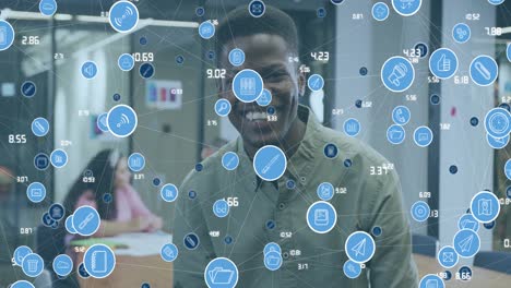 Animation-of-connected-icons-with-numbers-over-smiling-african-american-man-in-office