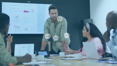 Animation-of-message-icons-floating-against-caucasian-man-talking-to-diverse-colleagues-at-office