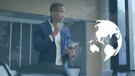 Animation-of-spinning-globe-and-world-map-over-african-american-businessman-using-digital-tablet