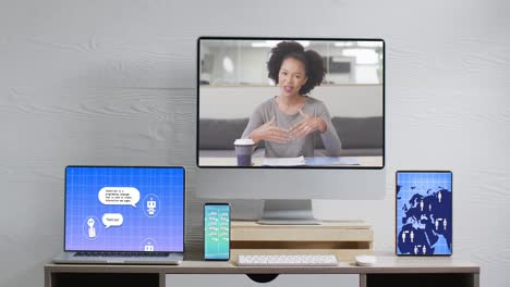 African-american-businesswoman-on-computer-video-call-with-data-processing-on-screens-in-office