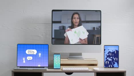 Biracial-businesswoman-on-video-call-and-electronic-devices-with-data-processing-on-screens