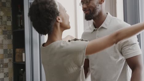 Happy-african-american-couple-holding-hands-and-dancing-in-ktichen-in-slow-motion