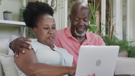 Glückliches-älteres-Afroamerikanisches-Paar,-Das-Laptop-In-Zeitlupe-Umarmt-Und-Benutzt