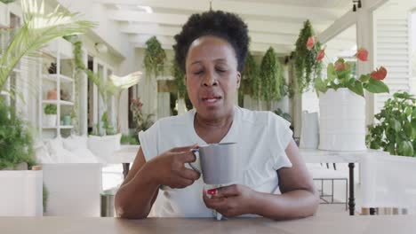 Porträt-Einer-Glücklichen-älteren-Afroamerikanischen-Frau-Mit-Kaffee,-Die-Einen-Videoanruf-In-Zeitlupe-Führt