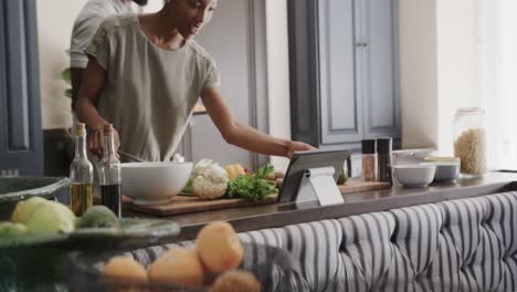 Happy-african-american-couple-cooking-and-using-tablet-in-ktichen-in-slow-motion