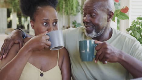 Happy-senior-african-american-couple-drinking-coffee-and-talking-in-slow-motion