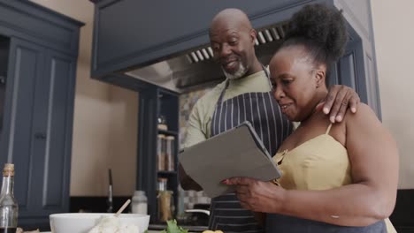 Happy-senior-african-american-couple-cooking-and-playing-tennis-in-slow-motion