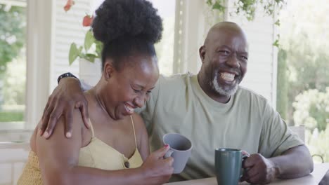 Happy-senior-african-american-couple-drinking-coffee-and-talking-in-slow-motion