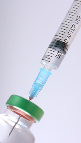 Vertical-video-of-insulin-vial-and-syringe-on-white-background,-slow-motion