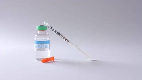 Close-up-of-insulin-vial-and-syringe-on-grey-background,-slow-motion