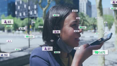 Animation-of-social-media-icons-and-numbers-over-biracial-woman-in-face-mask-with-smartphone