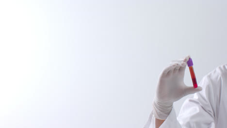 Hand-wearing-medical-glove-holding-blood-sample-on-white-background-with-copy-space,-slow-motion