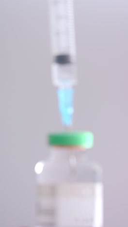 Vertical-video-of-insulin-vial-and-syringe-on-grey-background,-slow-motion