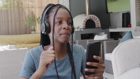Fröhliches-Afroamerikanisches-Teenager-Mädchen-Mit-Kopfhörern,-Das-Mit-Dem-Smartphone-Musik-Hört