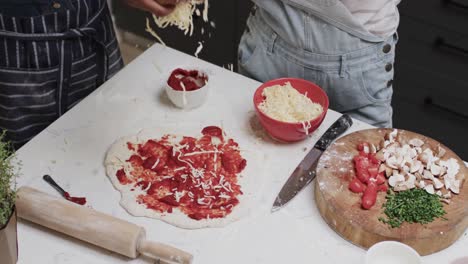 Midsection-of-diverse-teenage-female-friends-preparing-pizza-base-in-slow-motion