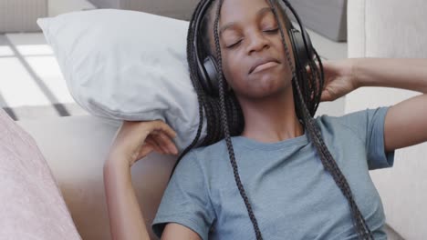 Happy-african-american-teenage-girl-wearing-headphones-listening-to-music