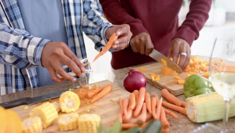 Midsection-off-african-american-gay-male-couple-preparing-dinner,-chopping-vegetables,-slow-motion