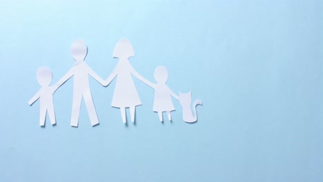 Close-up-of-family-with-cat-made-of-white-paper-on-blue-background-with-copy-space