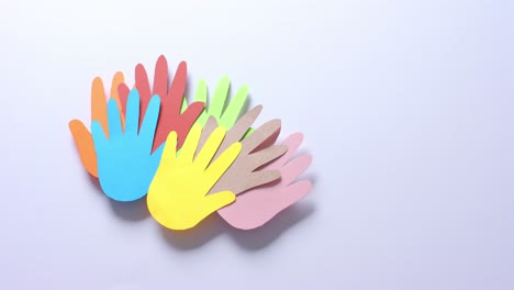 Close-up-of-hands-together-made-of-colourful-paper-on-white-background-with-copy-space