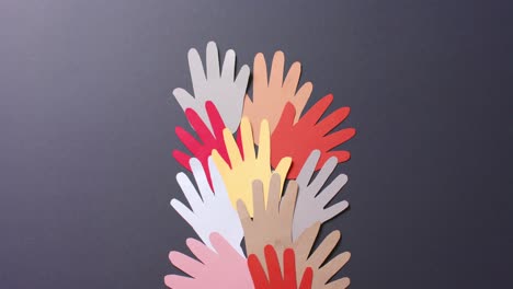 Close-up-of-hands-together-made-of-colourful-paper-on-gray-background-with-copy-space