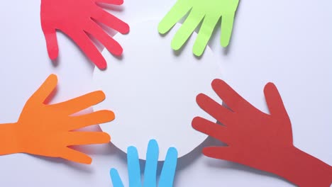 Close-up-of-hands-touching-circle-made-of-colourful-paper-on-white-background-with-copy-space