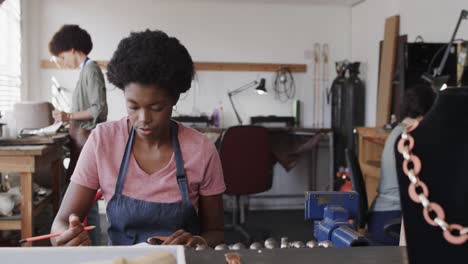 Vielbeschäftigte-Afroamerikanische-Arbeiterin-Zeichnet-Schmuckdesign-Im-Schmuckstudio-In-Zeitlupe
