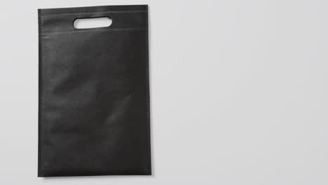 Nahaufnahme-Einer-Schwarzen-Tasche-Auf-Weißem-Hintergrund,-Kopierraum,-Zeitlupe