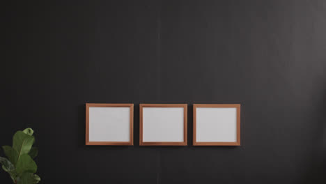 Drei-Holzrahmen-Mit-Kopierraum-Auf-Weißem-Hintergrund,-Sofa-Und-Pflanze-Und-Schwarzer-Wand