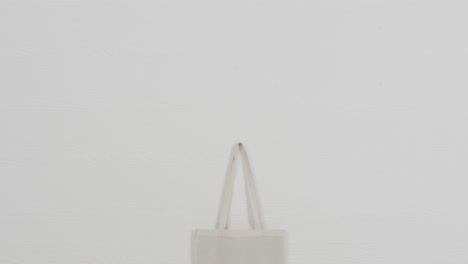 Close-up-of-white-bag-on-white-background,-copy-space,-slow-motion