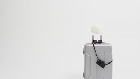 Close-up-of-suitcase,-camera,-sunglasses-and-sunhat-with-copy-space-on-white-background