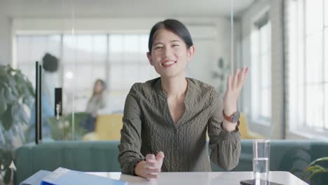 Retrato-De-Una-Feliz-Mujer-De-Negocios-Asiática-Casual-Saludando-Durante-Una-Videollamada-En-La-Oficina,-Cámara-Lenta