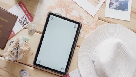 Flat-lay-of-tablet-with-copy-space,-passport-and-sunhat-on-wooden-background
