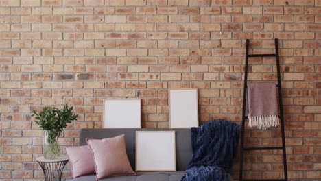 Three-wooden-frames,-plant-and-sofa-with-copy-space-on-brick-wall