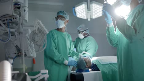 Verschiedene-Chirurgen-Mit-Gesichtsmasken,-Die-In-Zeitlupe-Eine-Sauerstoffmaske-Am-Patienten-Im-Operationssaal-Verwenden