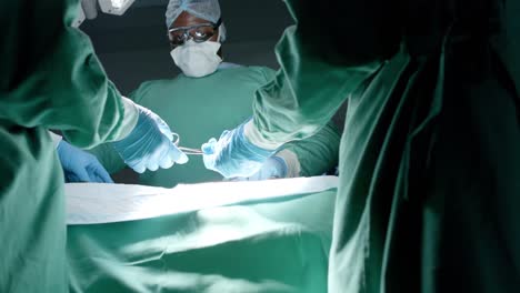 Diverse-surgeons-with-face-masks-during-surgery-in-operating-room-in-slow-motion