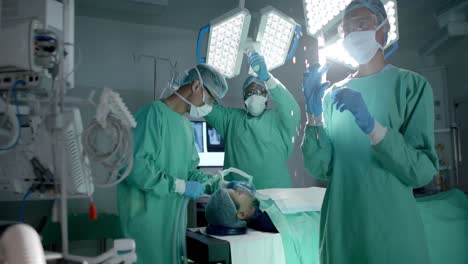 Diverse-surgeons-with-face-masks-using-oxygen-mask-on-patient-in-operating-room-in-slow-motion
